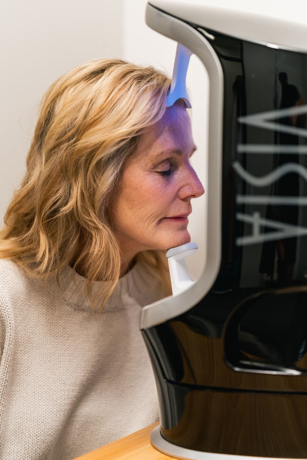 A guest resting her chin in the Visia booth during a Carroll Cosmetic Club consultation