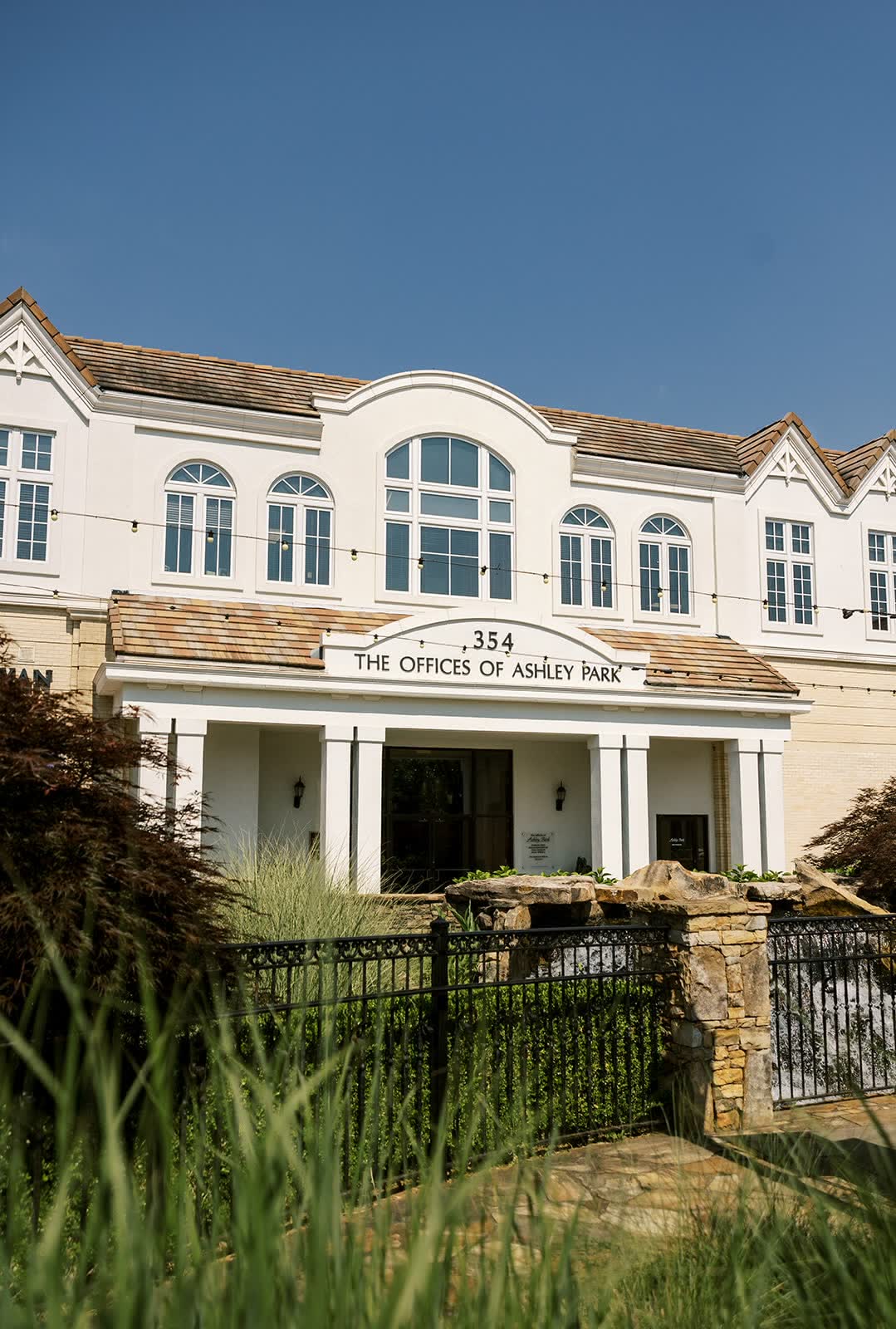 The front of The Offices of Ashley Park, number 354, with a columned entrance behind a stone and iron fence