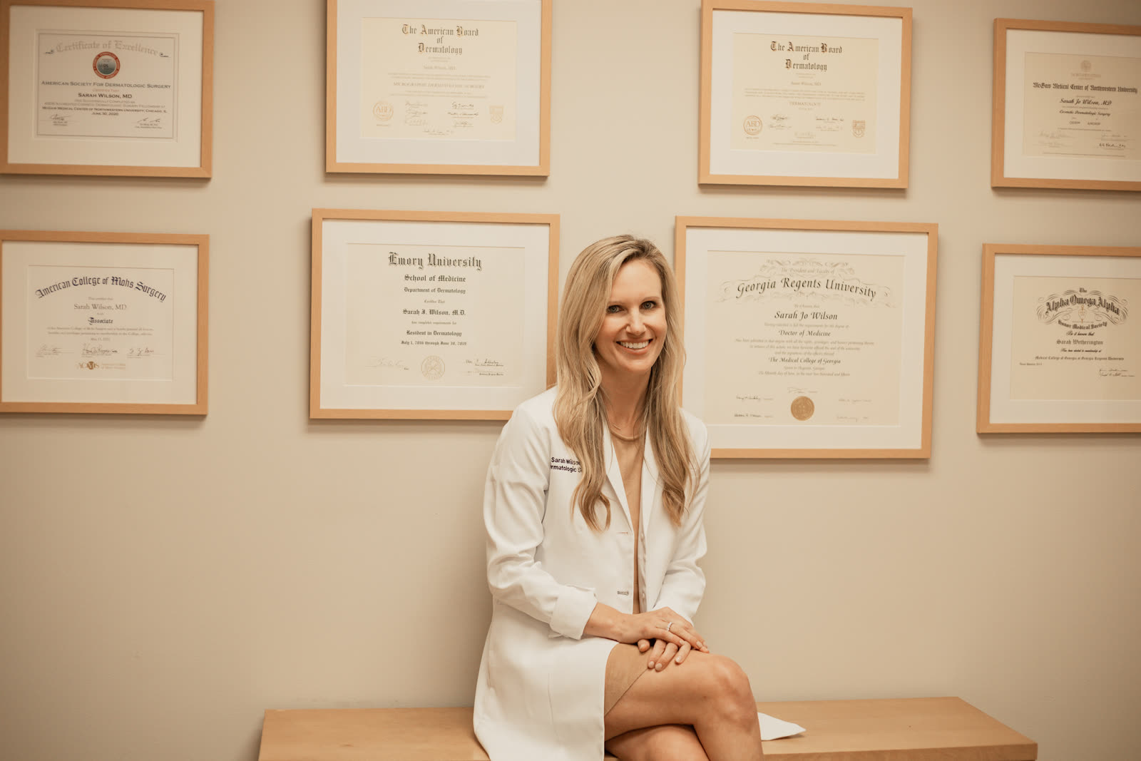 Dr. Sarah Wilson seated in front of her framed medical school, residency, and board certification diplomas