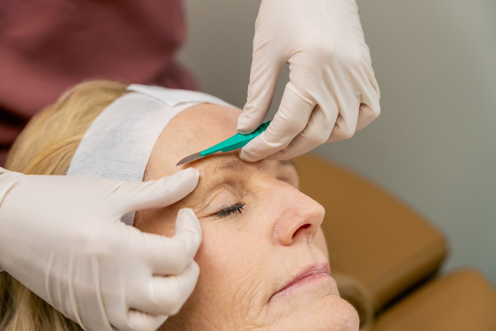 Aesthetician performing a dermaplaning treatment on a guest's forehead