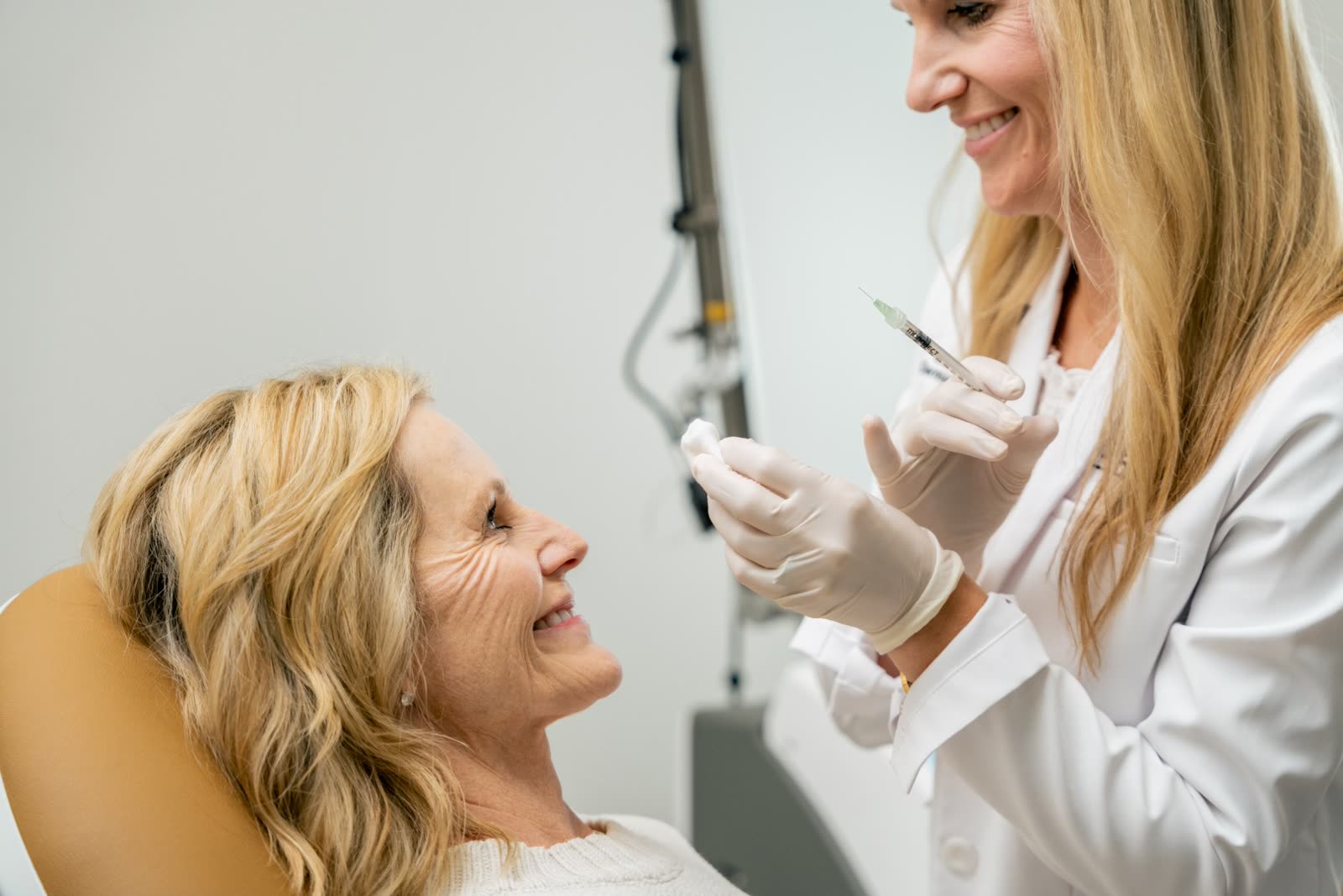 Cosmetic nurse injector talking a smiling guest through a Dysport treatment